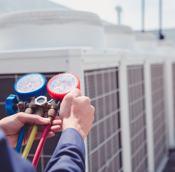 Person holding HVAC gauge set outdoors.