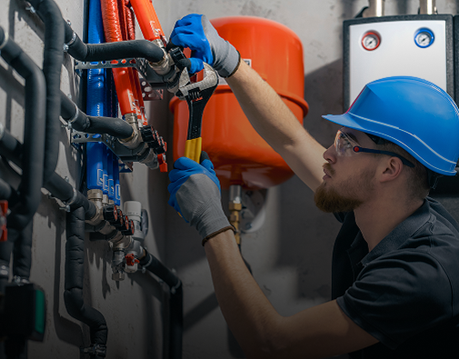 Worker repairing pipes in industrial setting.